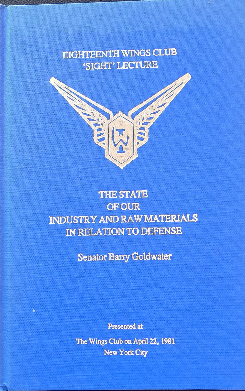 Blue clothbound book cover with a silver winged Wings Club emblem, printed Eighteenth Wings Club Sight Lecture, The State of Our Industry and Raw Materials in Relation to Defense, Senator Barry Goldwater, presented at The Wings Club on April 22, 1981, New York City