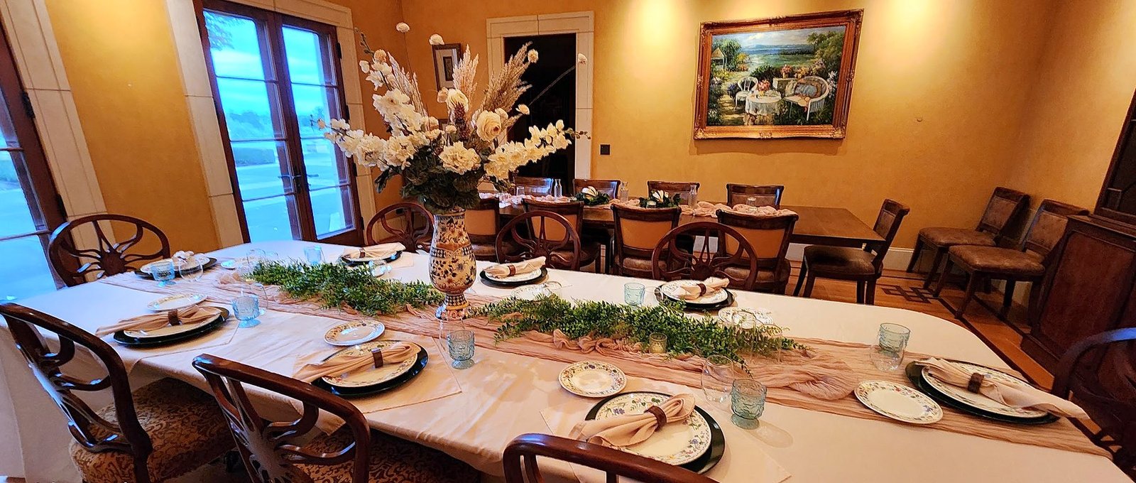 Dining room with long table set with greenery